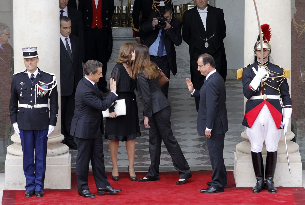 France's president Nicolas Sarkozy (L) salutes his successor Francois Hollande (R) as French First Lady Carla Bruni (2ndR) kisses Valerie Trierweiler (2ndL), companion of France's President-elect as Sarkozy and his wife is about to leave the Elysee presid
