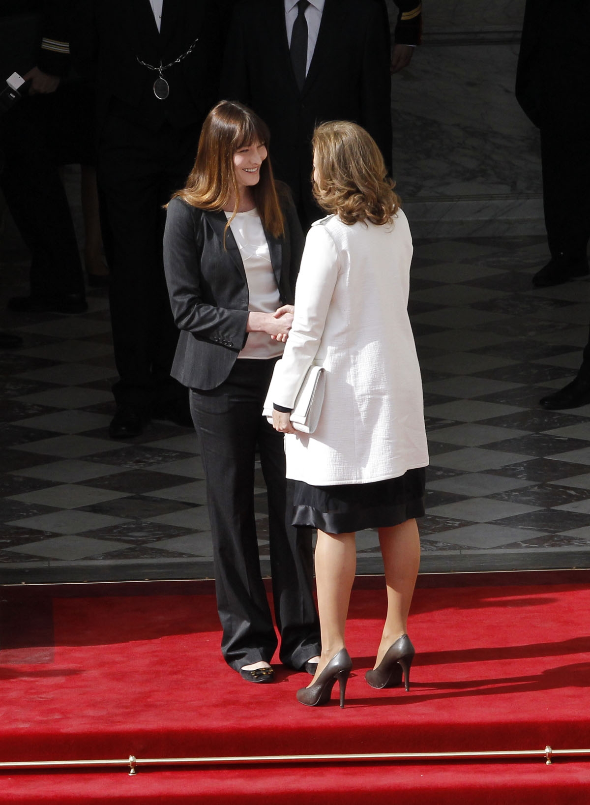 French outgoing First Lady Carla Bruni (L) welcomes Valerie Trierweiler, companion of France's President-elect Francois Hollande, prior to the start of the investiture ceremony between France's president Francois Hollande and his predecessor Nicolas Sarko