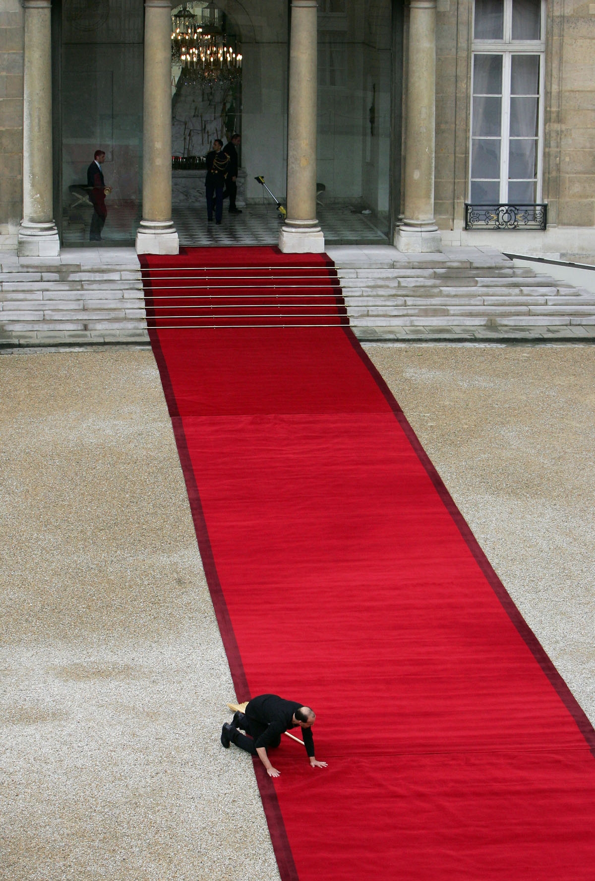An employee places a red carpet in the Elysee Palace courtyard, 16 May 2007 in Paris, before the handover power ceremony between outgoing French President Jacques Chirac and president-elect Nicolas Sarkozy.