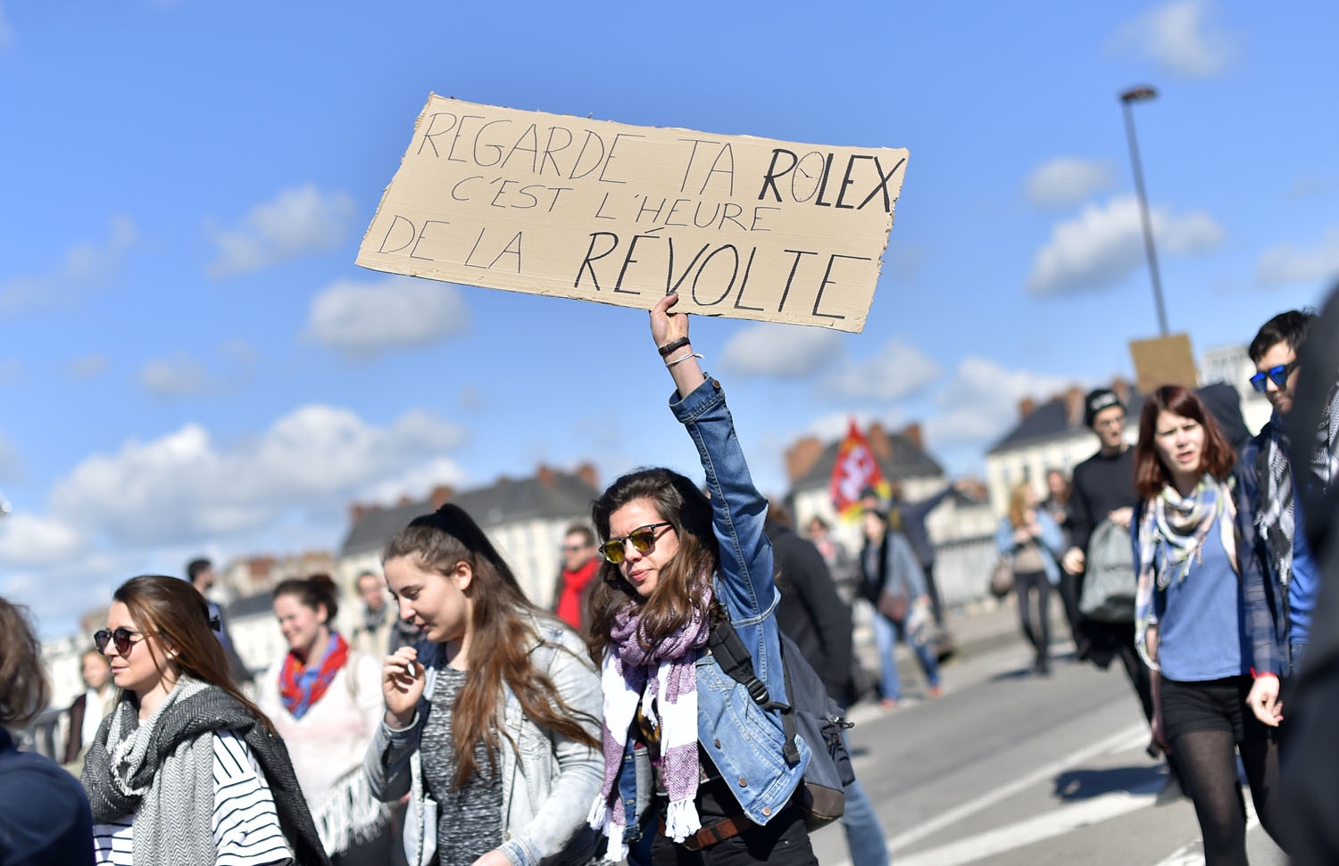 A demonstrator holds a placard reading Check your Rolex wristwatch, the time of rebellion has come as people take part in a protest against the French government's proposed labour reforms on April 28, 2016 in Nantes, western France. Protests turned viole A demonstrator holds a placard reading Check your Rolex wristwatch, the time of rebellion has come as people take part in a protest against the French government's proposed labour reforms on April 28, 2016 in Nantes, western France. Protests turned viole