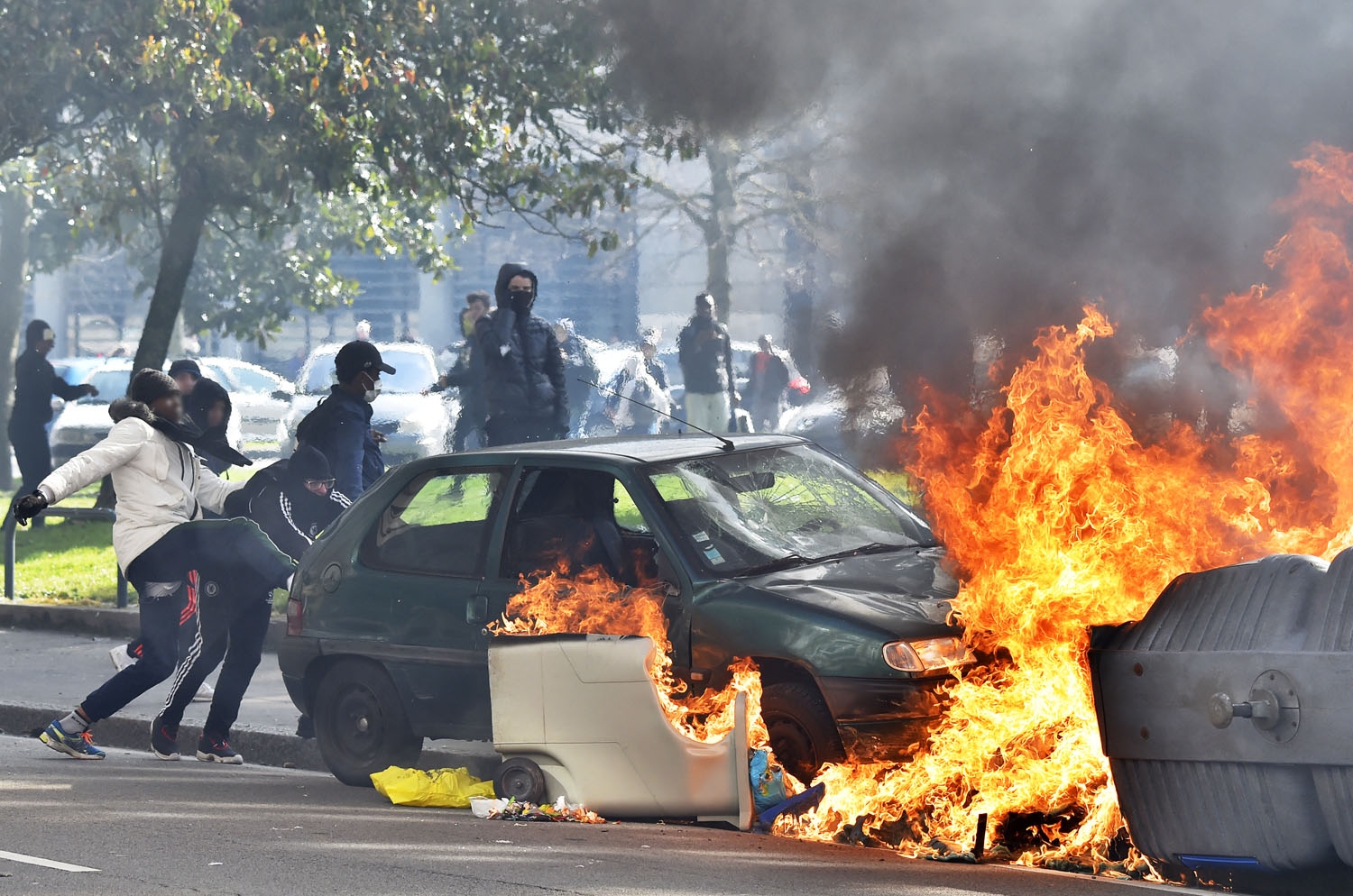 People push a damaged car towards a garbage set on fire during a protest by unions and students on March 31, 2016 in Nantes, western France People push a damaged car towards a garbage set on fire during a protest by unions and students on March 31, 2016 in Nantes, western France