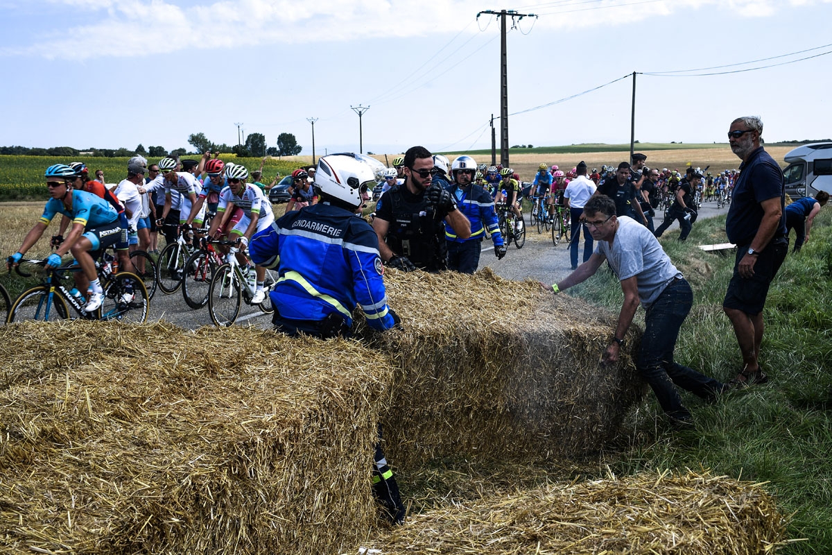 Gendarmes remove haystacks from the route as the pack rides behind, during a farmers' protest who attempted to block the stage's route, during the 16th stage of the 105th edition of the Tour de France cycling race, between Carcassonne and Bagneres-de-Luch