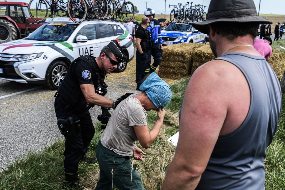 A protester (C) reacts after scuffling with gendarmes (R and L) during a farmers' protest who attempted to block the stage's route, during the 16th stage of the 105th edition of the Tour de France cycling race, between Carcassonne and Bagneres-de-Luchon,