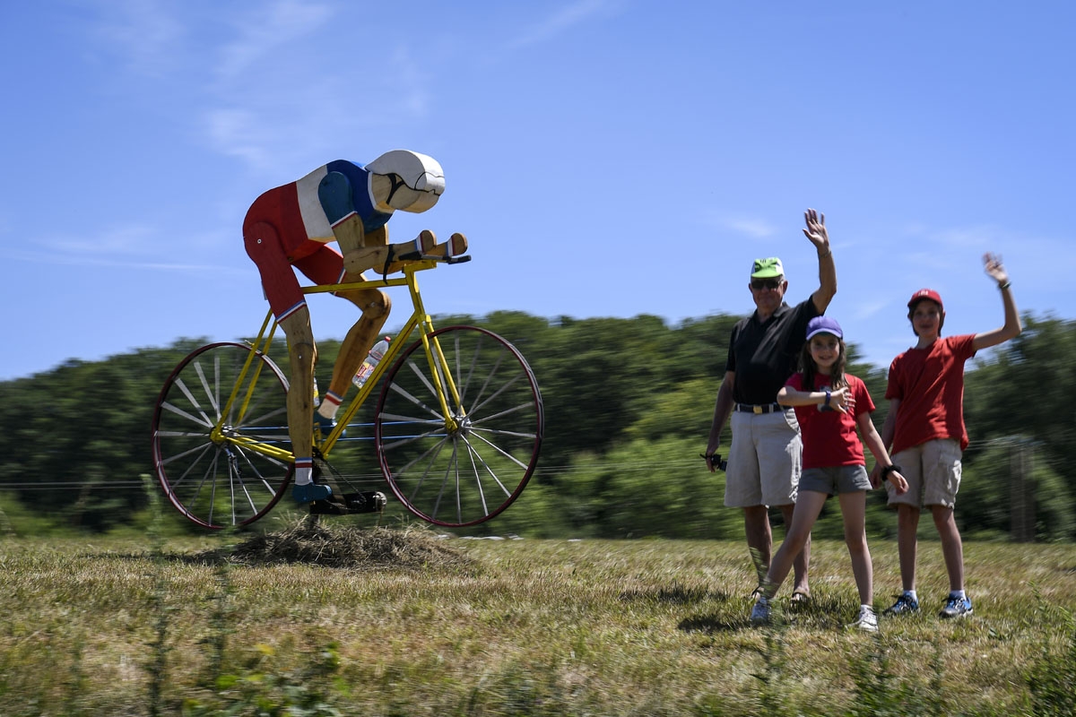 Supporters cheer along the road next to a giant wooden sculpture shaped as a cyclist during the 160,5 km fifth stage of the 104th edition of the Tour de France cycling race on July 5, 2017 between Vittel and La Planche des Belles Filles.