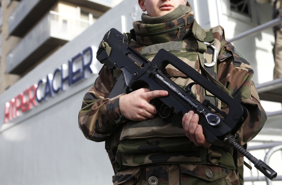 A French soldier stands guard during the posing of a commemorative plaque on the Hyper Cacher Jewish supermarket in Paris on January 4, 2016, in memory of four people killed during a hostage taking in the shop on January 9, 2015.