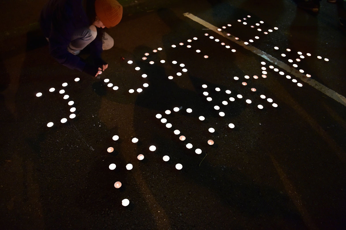 A person places a candle to complete the call 'Justice Adama' during a gathering in memory of the late 24-year-old Adama Traore who died during his arrest by the police in July 2016 in Beaumont-sur-Oise, outside the city hall of Beaumont-sur-Oise, north o