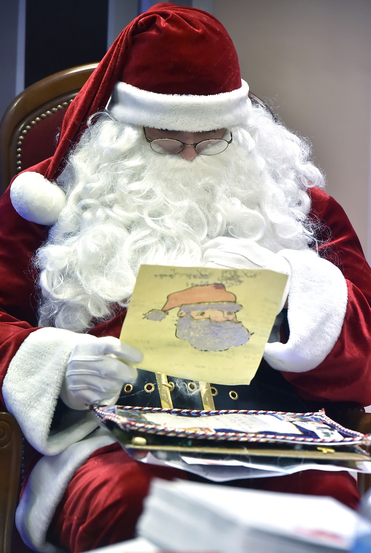 A man dressed as Santa Claus looks at letters prior to distribute them to people in charge of answering letters addressed to Santa Claus at a mail sorting office in Libourne, southwestern France, on December 20, 2016.