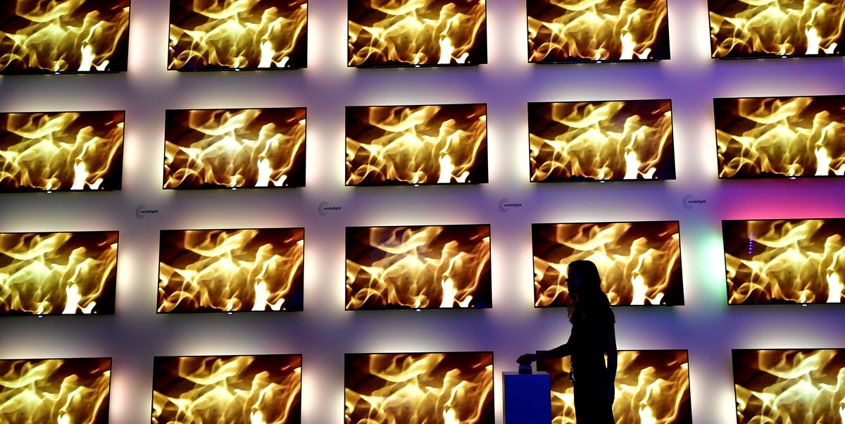 A fair worker stands next to an installation of televisions equipped with the ambilight lighting system developed by Philips at the IFA Consumer Electronics Fair in Berlin in Berlin on August 31, 2017.