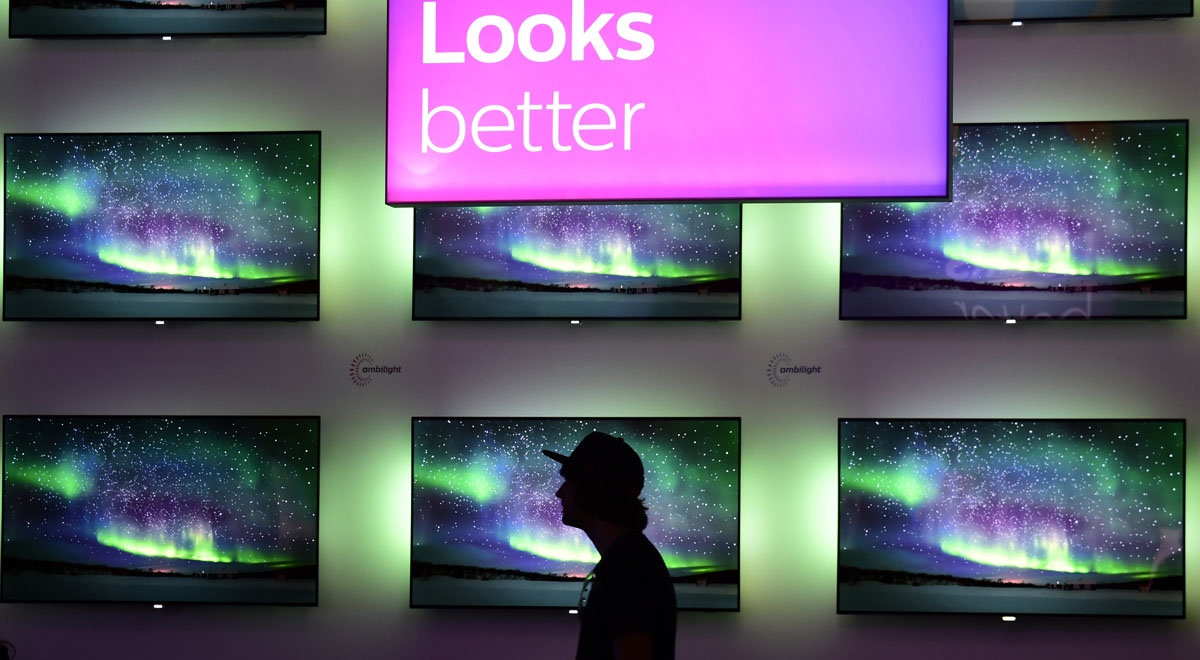 A man walks past an installation of televisions equipped with the ambilight lighting system developed by Philips at the IFA Consumer Electronics Fair in Berlin in Berlin on August 31, 2017.