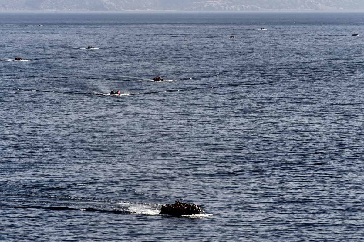 Refugees and migrants aboard dinghies reach the Greek island of Lesbos after crossing the Aegean sea from Turkey on October 4, 2015.