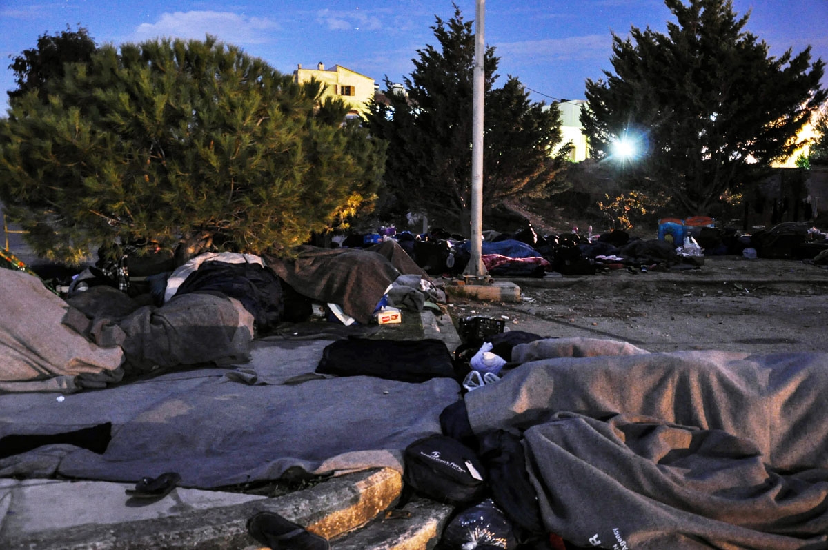 Refugees sleep on the ground at Souda refugee camp on the island of Chios early on November 20, 2016, after several migrants were left without a shelter after assailants wielding rocks and firebombs targeted them.