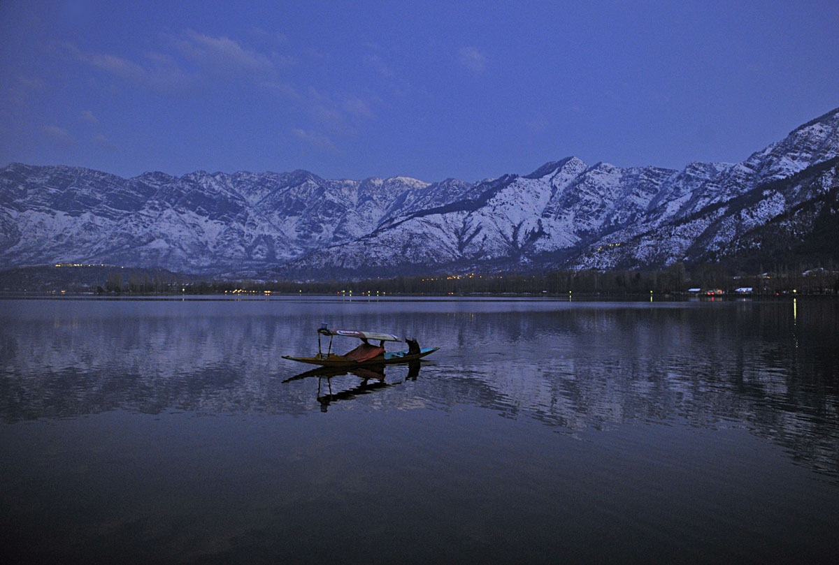 A boat passes in front of snow-covered mountains, on the Dal Lake, in Srinagar on January 1, 2011.