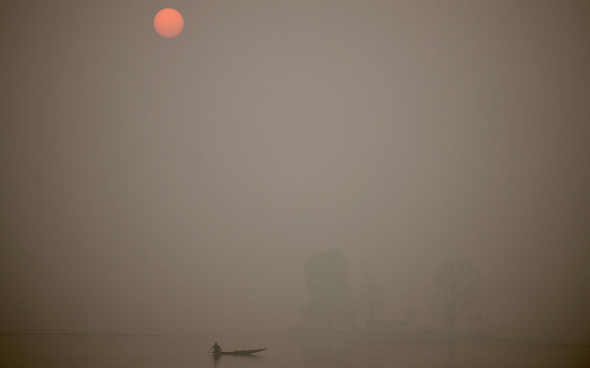 A Kashmiri fisherman rows his boat on Dal Lake at sunset on a cold, winter's day in Srinagar on November 23, 2016.