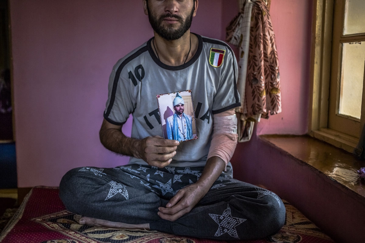 In this photo taken on September 9, 2016, Kashmiri resident Zahoor Ahmed Mangoo, the brother of lecturer Shabir Ahmed Mangoo, who was beaten to death by Indian Army personnel from the 50 Rashtriya Rifles, poses holding a photograph of his brother at his h