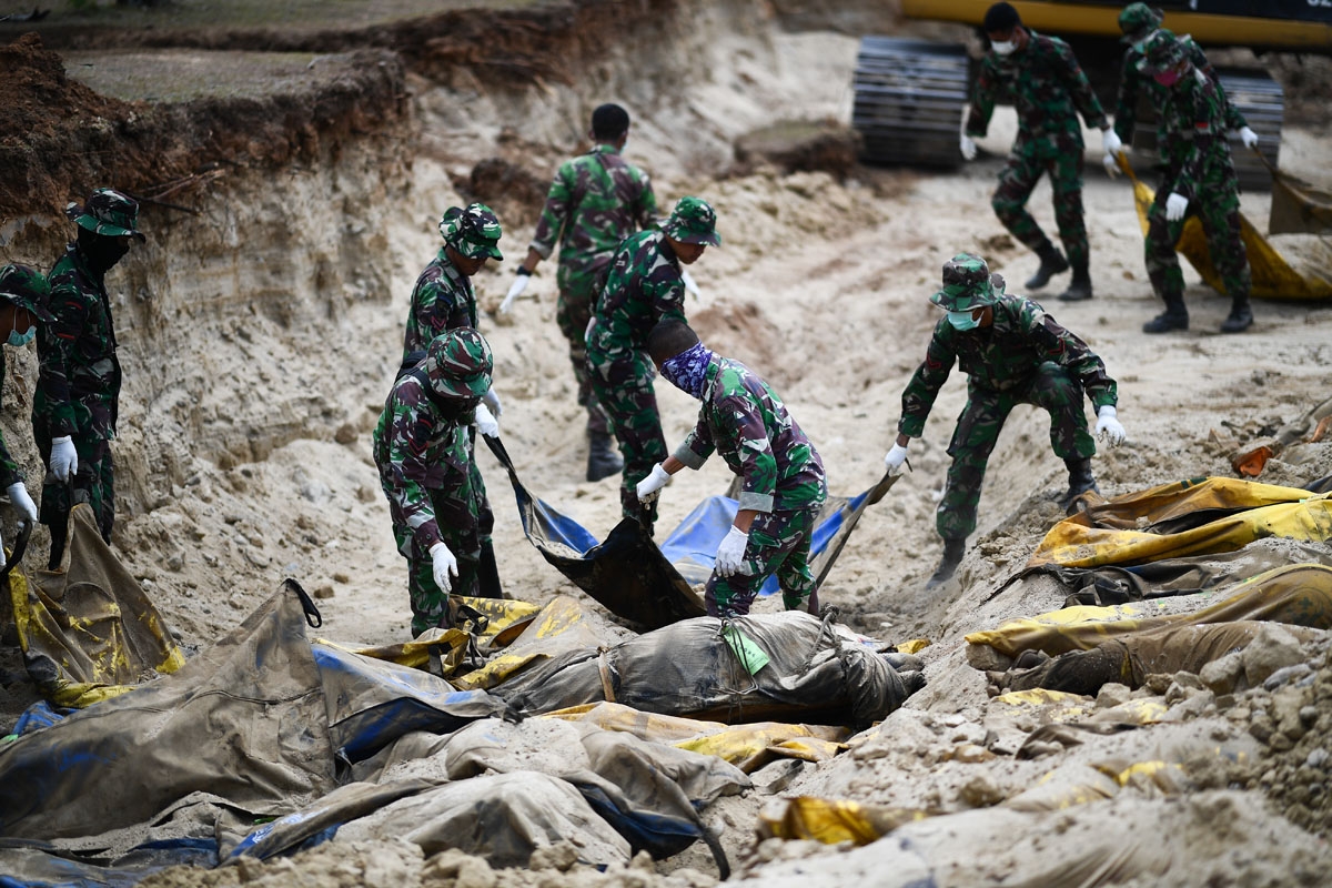 Indonesian soldiers bury quake victims in a mass grave in Poboya in Indonesia's Central Sulawesi on October 2, 2018.