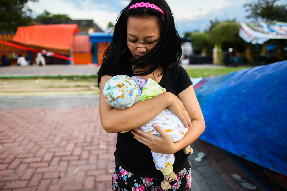 A quake survivor cradles her two-month-old son at a makeshift camp in Palu in Indonesia's Central Sulawesi on October 2, 2018.