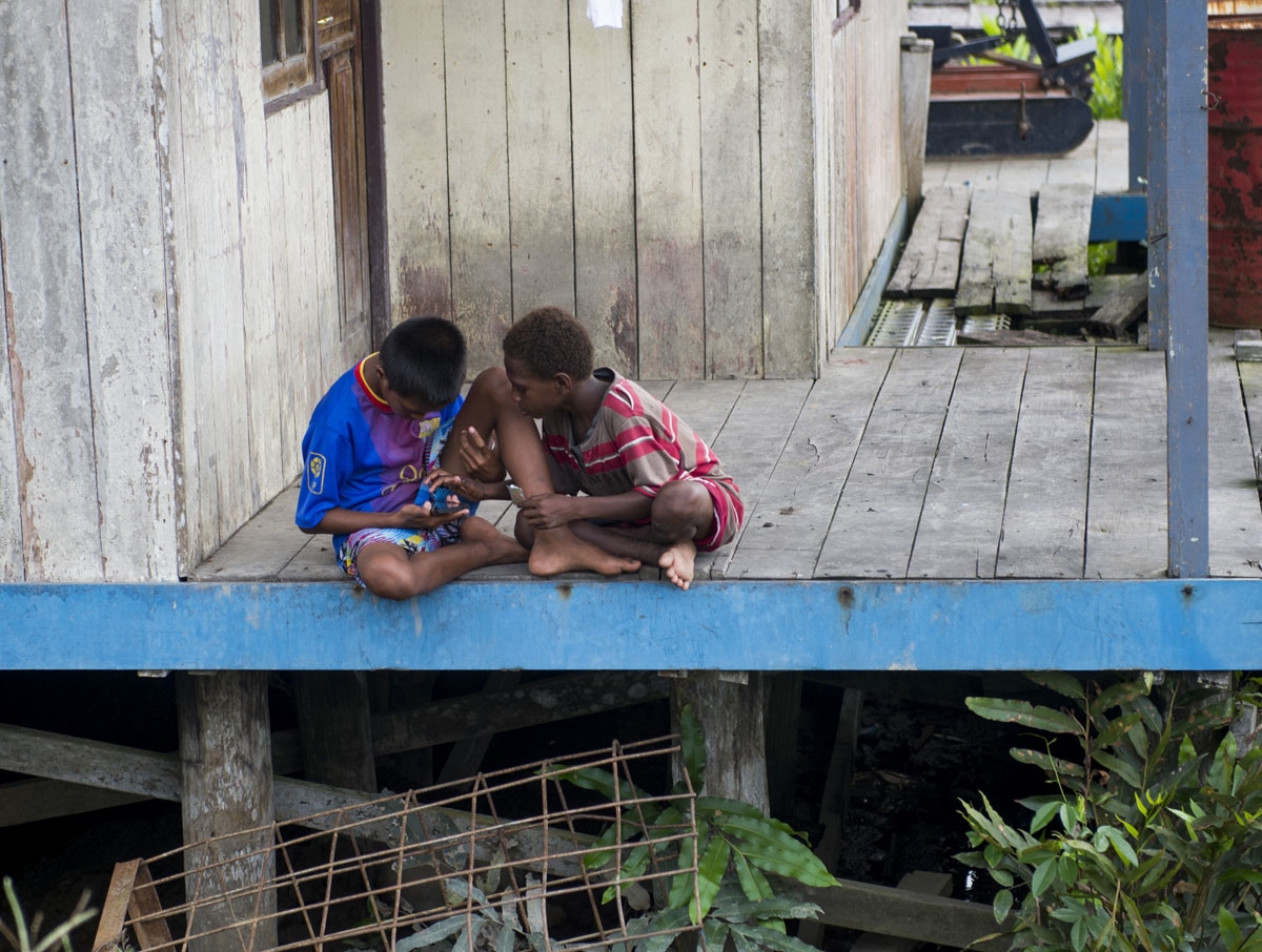 Two Papuan boys play with a phone in Agats, Asmat district, in West Papua on January 27, 2018.