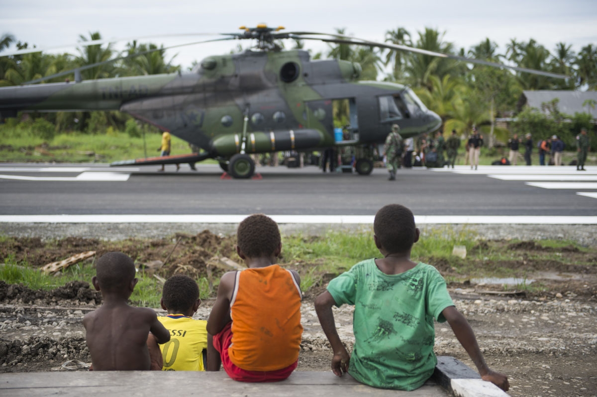 Three Papuan boys watch an Indonesian military Mi17 helicopter at Erwer airport in Agats, Asmat district, in West Papua on January 27, 2018.
