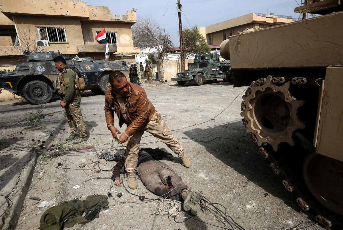 Iraqi forces stand next to the body of an alleged Islamic State (IS) group fighter as they advance through Mosul's Jawasaq neighbourhood on February 27, 2017, during an offensive to retake the area from the jihadists.