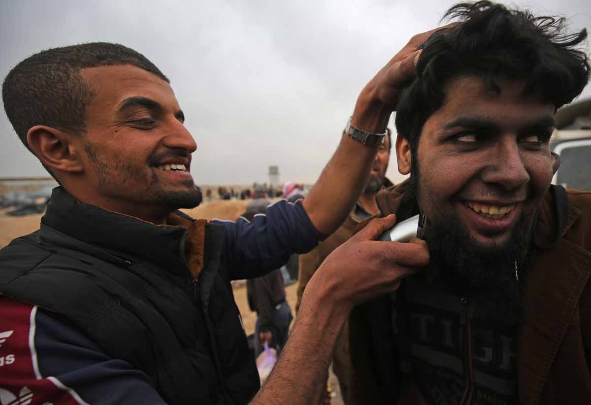 An Iraqi man displaced from the city of Mosul shaves off a man's beard following their arrival at a camp in the Hamam al-Alil area south of the embattled city on March 11, 2017, during the government forces ongoing offensive to retake the area from Islami