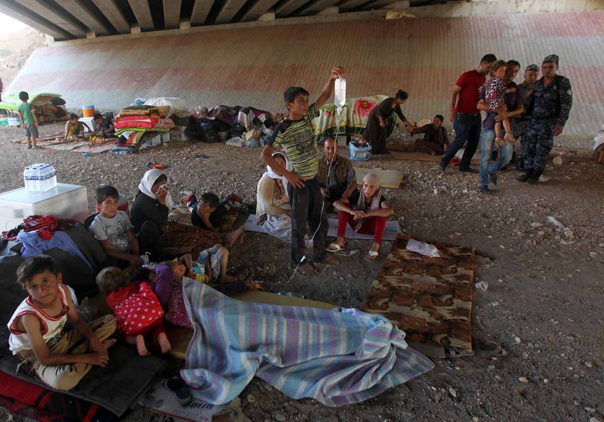 Iraqi Yazidis, who fled their homes a week ago when Islamic State (IS) militants attacked the town of Sinjar, gather at a makeshift shelter on August 10, 2014 in the Kurdish city of Dohuk in Iraq's autonomous Kurdistan region
