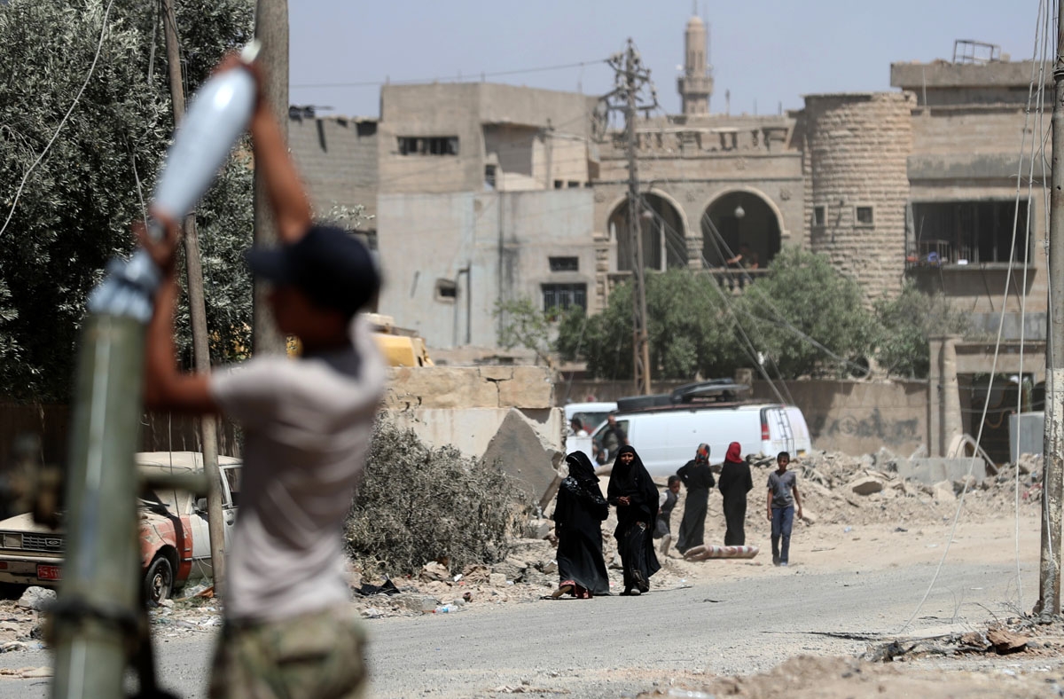 A member of the Iraqi forces loads a mortar as displaced residents evacuate from western Mosul's Zanjili neighbourhoodm, as government forces advance in the area during their ongoing battle against Islamic State (IS) group fighters on May 31, 2017.