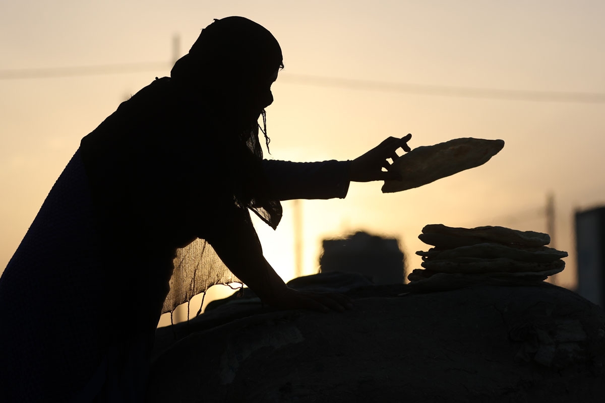 An Iraqi woman bakes bread at the Al-Khazir camp for internally displaced people, located between Arbil and Mosul, on June 6, 2017.