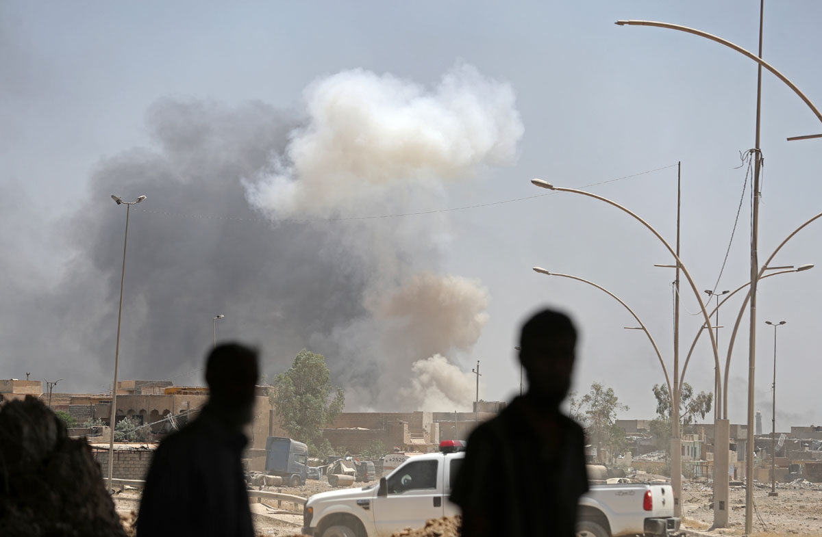 Iraqis look at smoke billowing from a building following a reported car bomb in western Mosul's Zanjili neighbourhood on June 7, 2017