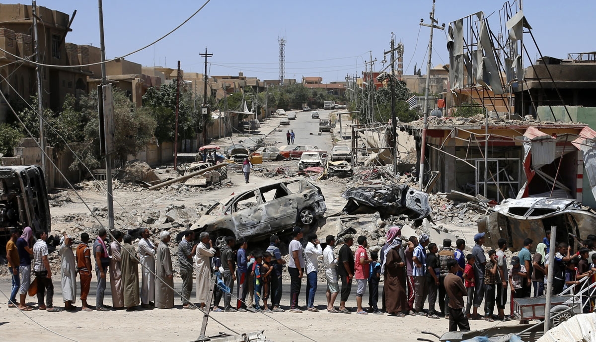 Iraqis stand in line to receive food aid in western Mosul's Zanjili neighbourhood on June 7, 2017, during ongoing battles as Iraqi forces try to retake the city from Islamic State (IS) group fighters.