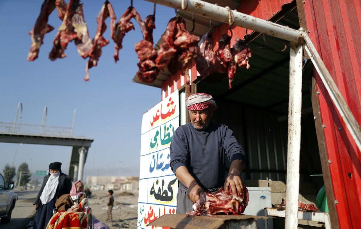 A butcher cuts a sheep into pieces as displaced Iraqi families, who fled their home, wait to be transferred to a camp, on November 28, 2016 in the village of Gogjali,