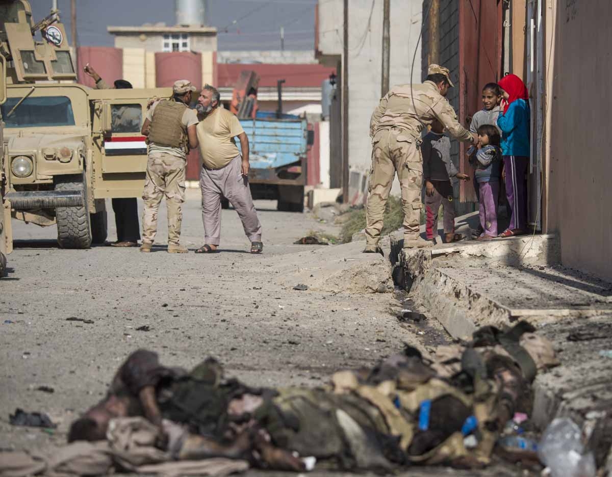 Soldiers from the Iraqi army 9th armoured division greet residents as bodies of Islamic State (IS) group fighters litter a street in the eastern Al-Intissar neighbourhood of Mosul on November 6, 2016. Soldiers from the Iraqi army 9th armoured division greet residents as bodies of Islamic State (IS) group fighters litter a street in the eastern Al-Intissar neighbourhood of Mosul on November 6, 2016.