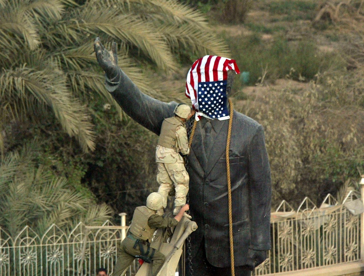 US Marines cover the statue of Iraqi President Saddam Hussein with the US flag in Baghdad's al-Fardous street 09 April 2003 as they prepare to bring it down. They removed it shortly afterwards and replaced it with an old Iraqi flag.