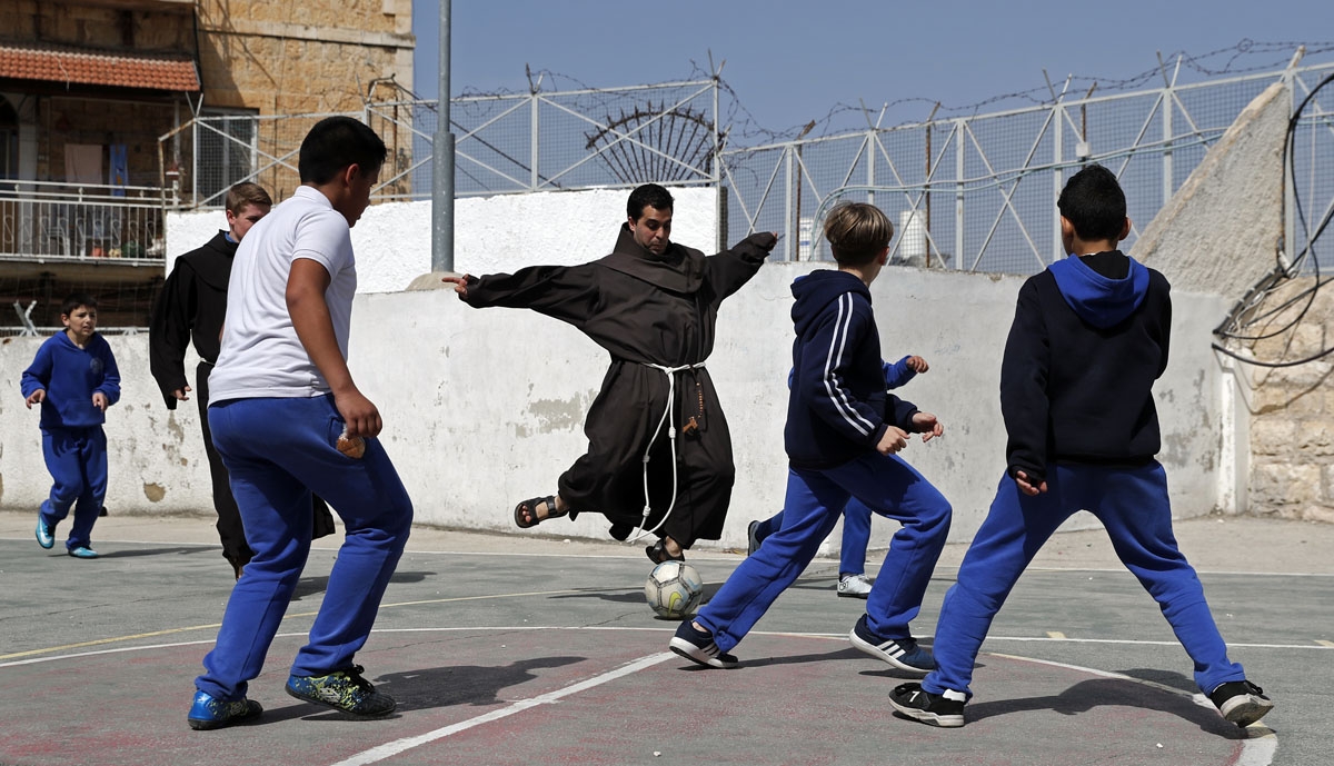 A Franciscan friar plays football with Palestinian children from the Terra Sancta school during a sport session in the Old City of Jerusalem, on March 1, 2018.