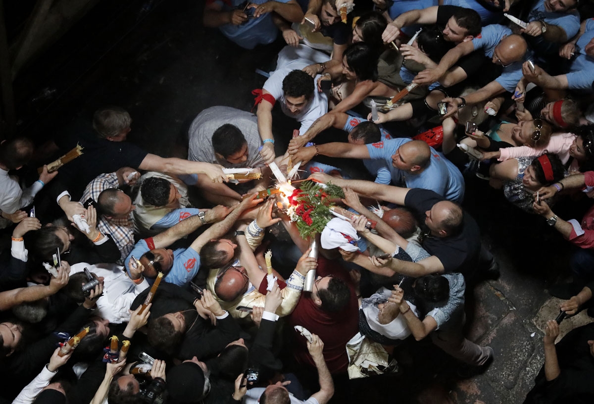 Christian Orthodox worshippers hold up candles lit from the Holy Fire as thousands gather in the Church of the Holy Sepulchre in Jerusalem's Old City, on April 30, 2016, during the Orthodox Easter ceremonies.