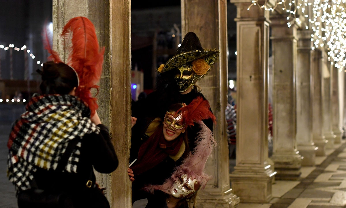 Revellers wearing traditional carnival costume pose in St Mark Square during Venice's Carnival on February 3, 2018.