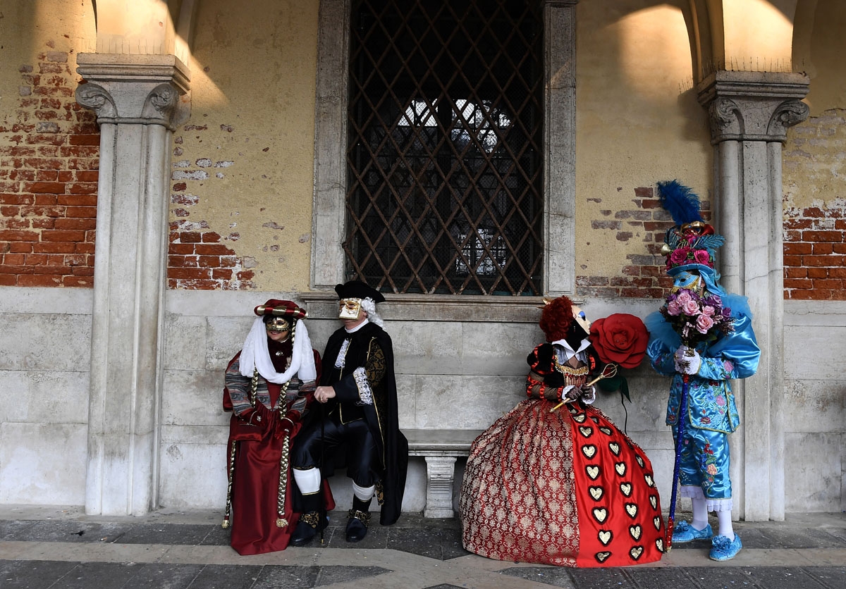 Masked revellers wearing traditional carnival costumes pose in Saint Mark Square during Venice's Carnival on February 4, 2018.