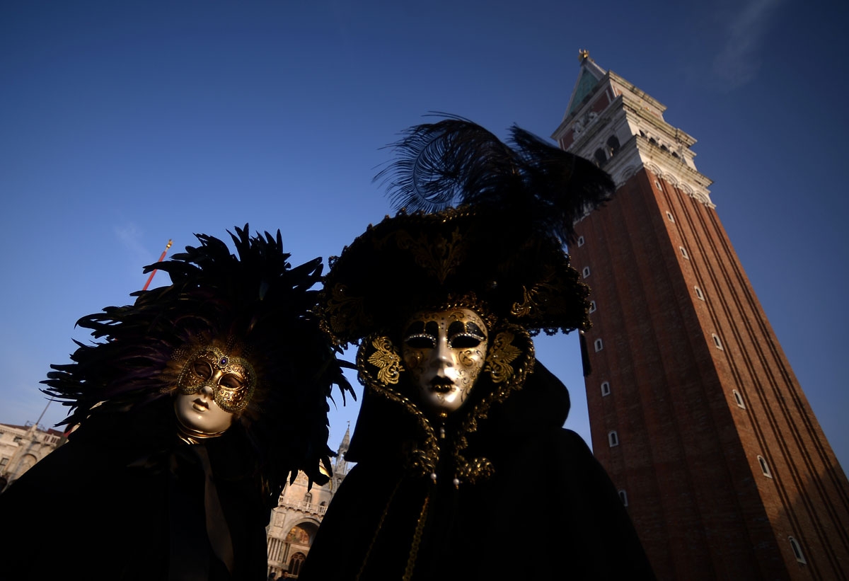 Masked revellers wearing traditional carnival costumes stand in St Mark Square during Venice's Carnival on January 28, 2018.