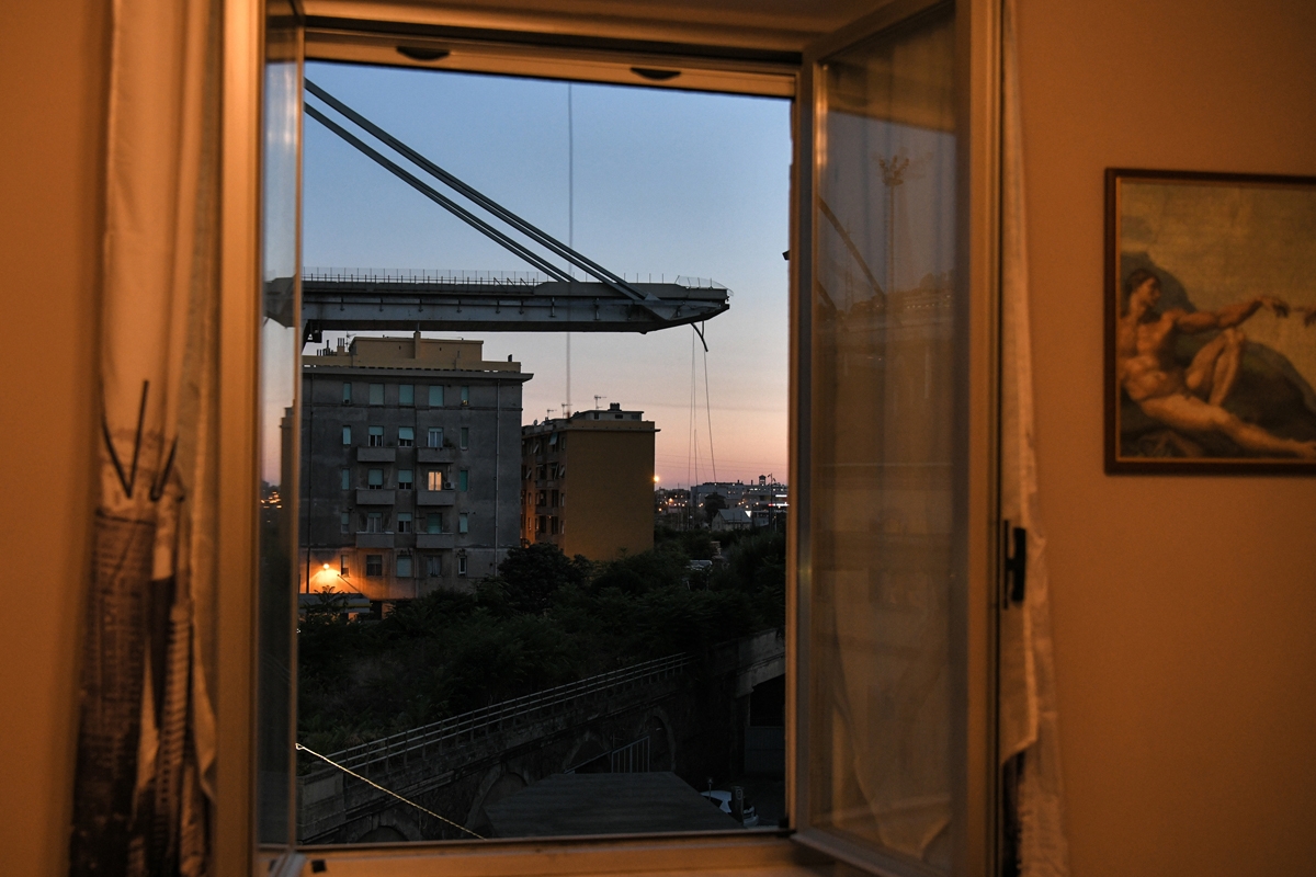 A general view taken through a window shows apartment buildings under the Morandi motorway bridge one day after a section collapsed in Genoa on August 15, 2018.
