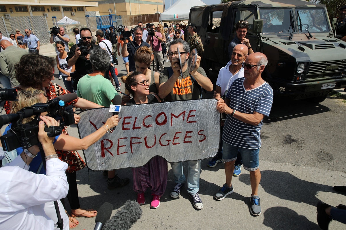 People hold a placard reading Welcom refugees as they protest against the visit of Italy's new hardline interior minister at the reception centre (CPSA) in Pozzallo, sicily, on June 3,2018.