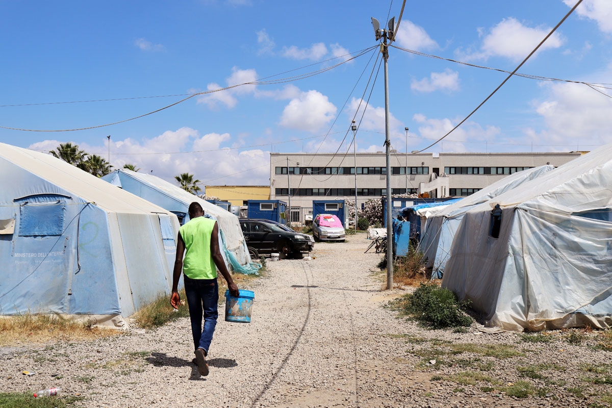 A man walks on June 5, 2018, in a migrant tent camp in the village of San Ferdinando, near Gioia Tauro, in the southern Italian region of Calabria.