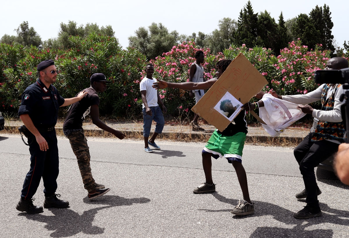 A picture taken on June 4, 2018 shows migrant farm-workers taking part in a protest in Gioia Tauro as they hold placards bearing the portrait of Soumaila Sacko, a 29-year-old Malian migrant farm worker was killed on the night of June 2 to 3 in a shootin