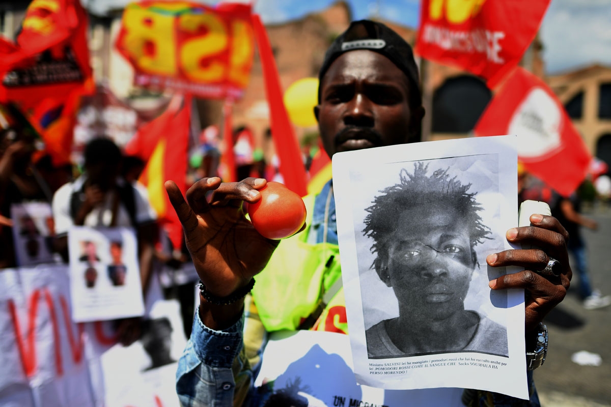 A demonstrator holds up a photo of Soumaila Sacko during a march organized by Italy's USB (Base Union of Trade Unions) against the murder of the USB syndicalist Sacko and the refusal by Italy to except migrants rescued at sea earlier in the week to land i