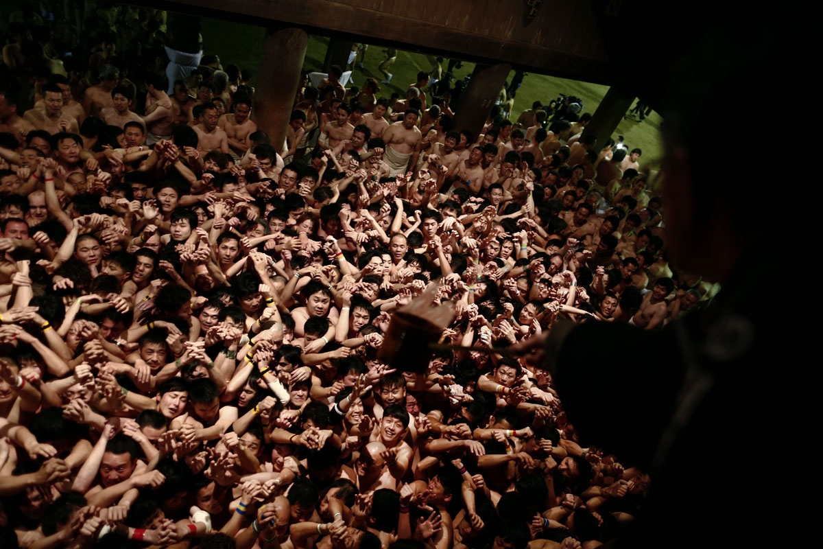 In this picture taken on February 18, 2017, a priest throws holy water to worshippers waiting to catch the sacred batons during the annual Naked Man Festival or 'Hadaka Matsuri' at Saidaiji Temple in Okayama, western Japan.