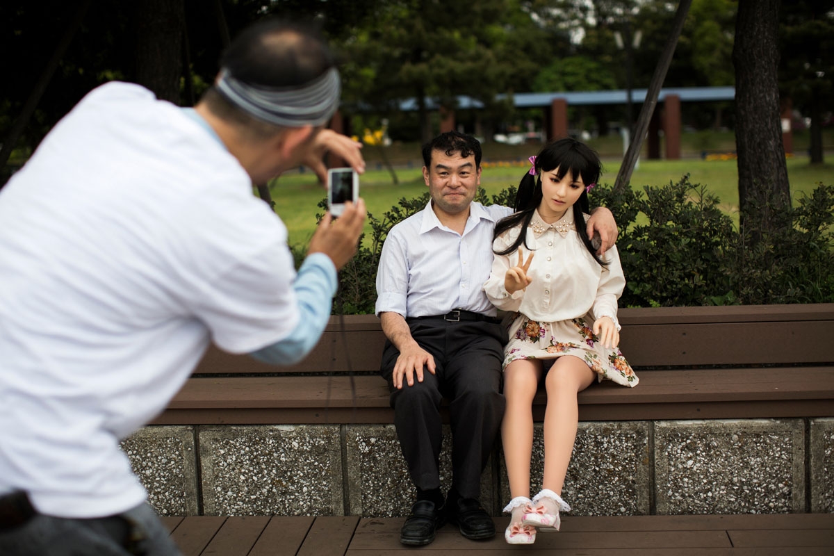 In this picture taken on May 9, 2017, a man takes pictures of physiotherapist Masayuki Ozaki and his silicone sex doll Mayu in Tokyo Bay.