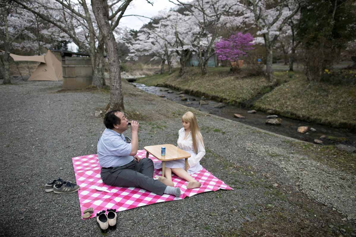 In this picture taken on April 21, 2017, 62-year-old Senji Nakajima (L) picnics with his silicone sex doll Saori under cherry blossoms in Yamanashi prefecture.