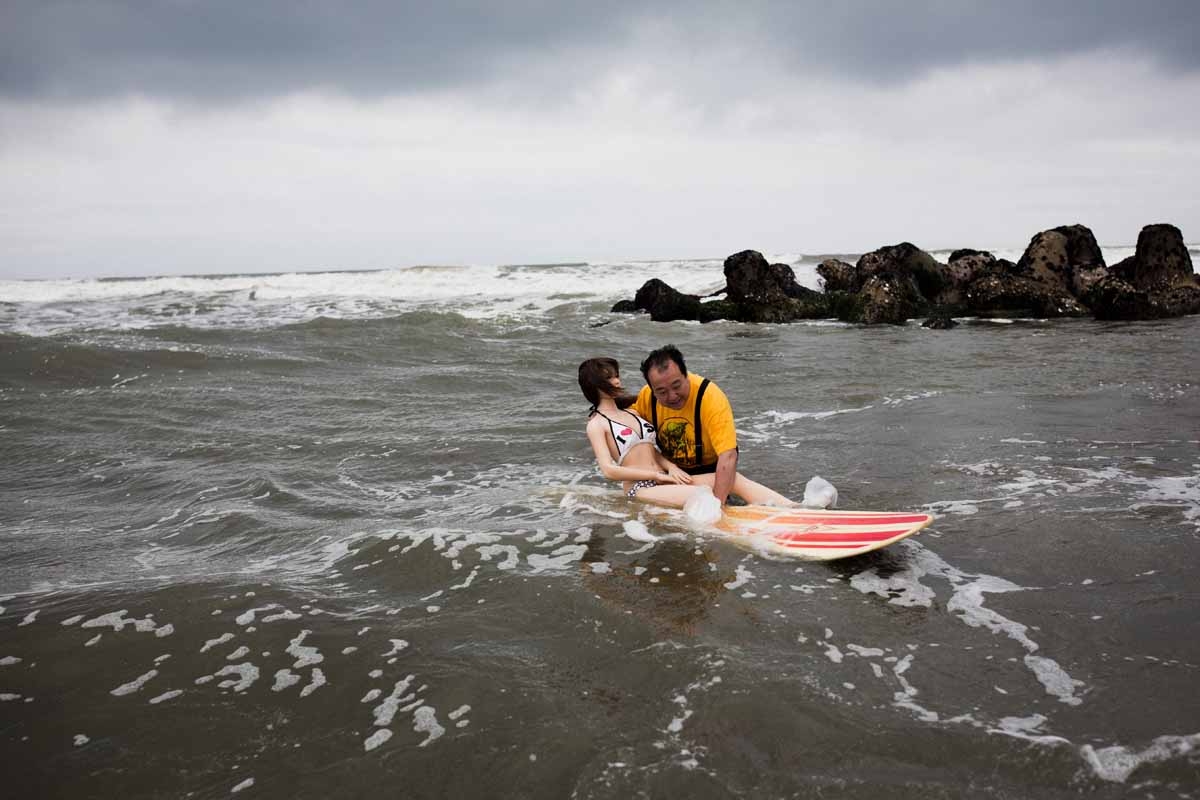 In this picture taken on June 14, 2017, 62-year-old Senji Nakajima tries to surf with his silicone sex doll Saori at Kujukuri beach, Chiba prefecture.