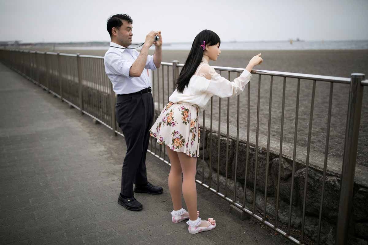 In this picture taken on May 9, 2017, physiotherapist Masayuki Ozaki (L) takes pictures of his silicone sex doll Mayu in Tokyo Bay.