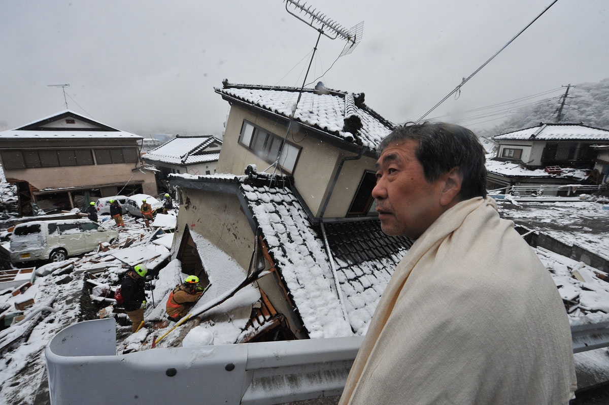 A man looks on as US rescue workers search for survivors in a house in Kamaishi, Iwate prefecture on March 16, 2011, after the devasting earthquake and ensuing tsunami on March 11. T