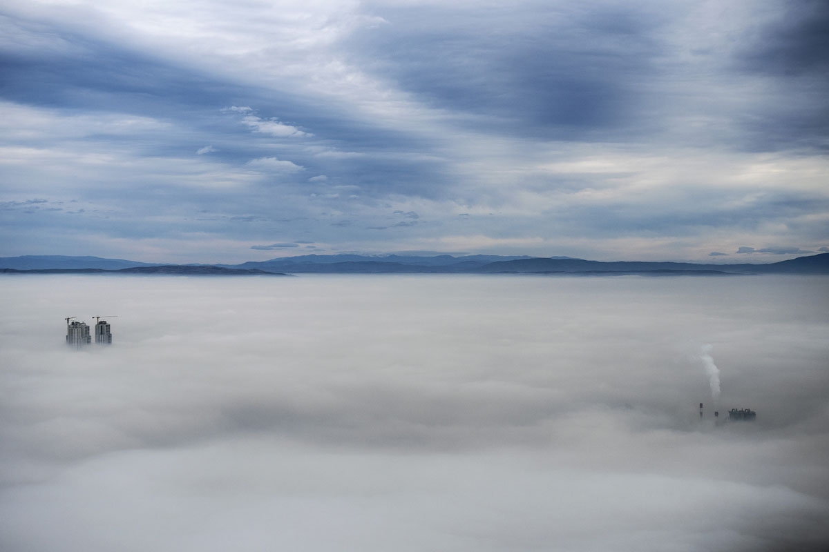 A picture taken from Vodno Mountain shows some of the city's highest buildings (L) and smoke rising from chimneys of a factory (R) in an area with a high level of air pollution in Skopje on December 15, 2017.