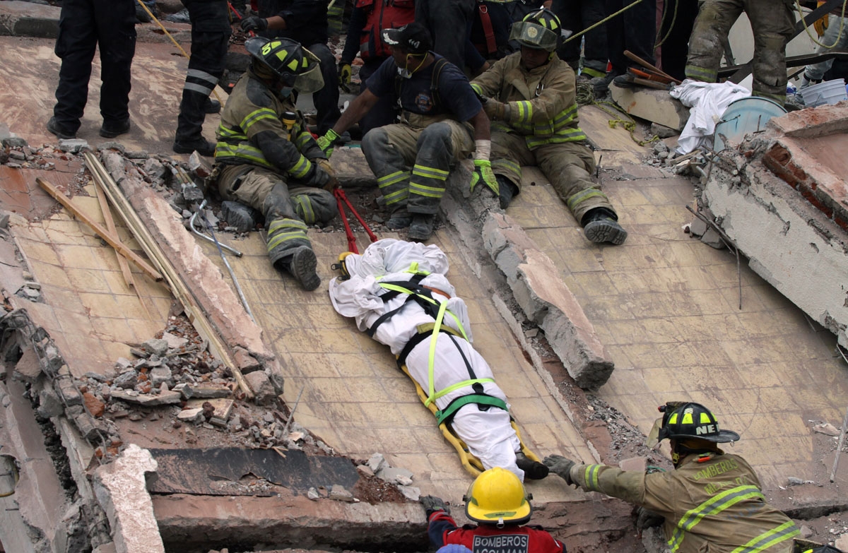 Rescuers and firefighters lower the corpse from a house that was destroyed after a powerful quake in Mexico City on September 20, 2017.